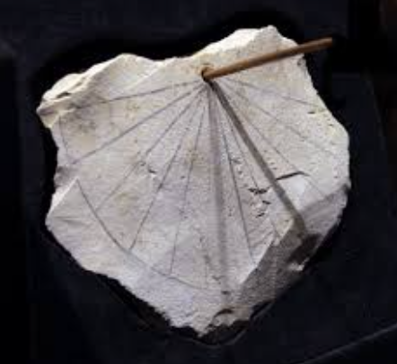 Ancient Egyptian sundial with central gnomon, casting a shadow across radial hour markers.