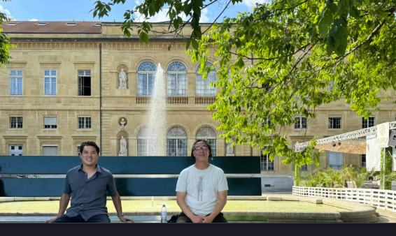 Two members of the Clockchain team seated by a fountain in Neuchâtel